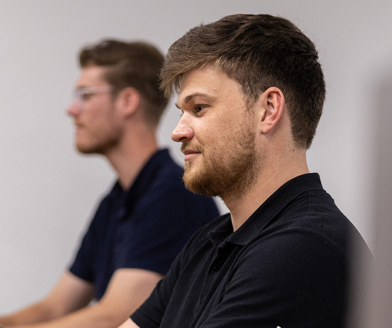 Side profile close-up portrait of two AI Advancements team members in dark polo shirts, illustrating the brand identity guidelines for AI Advancements