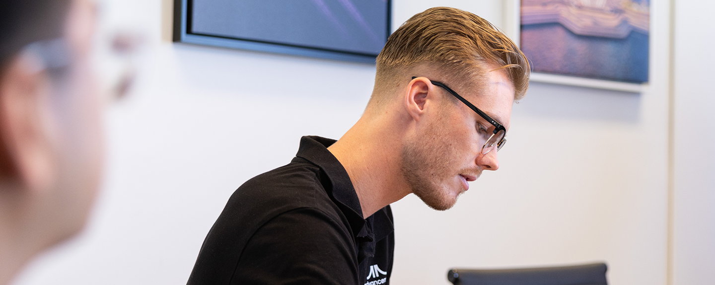 Side profile close-up of an AI Advancements team member with glasses and light hair concentrating on work in an office environment, representing AI for Leaders services