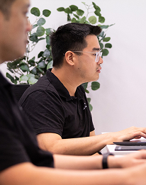 AI Advancements consultant focused on typing at a keyboard with potted plants visible in the office background, representing ChatGPT Workshop training sessions