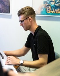 Professional with glasses working at a laptop or standing desk, representing the AI chatbot step to automate tasks while keeping humans in control