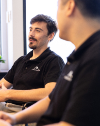 Two business professionals in dark shirts having a consultation meeting, representing the AI strategy step to deliver a board-ready AI roadmap