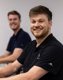 Two smiling AI professionals in dark shirts representing the AI strategy step to establish governance and readiness within an organisation