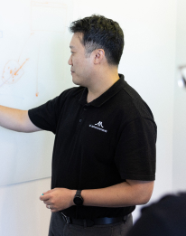 Professional in dark shirt presenting at a whiteboard, representing the AI strategy step to map the top use cases