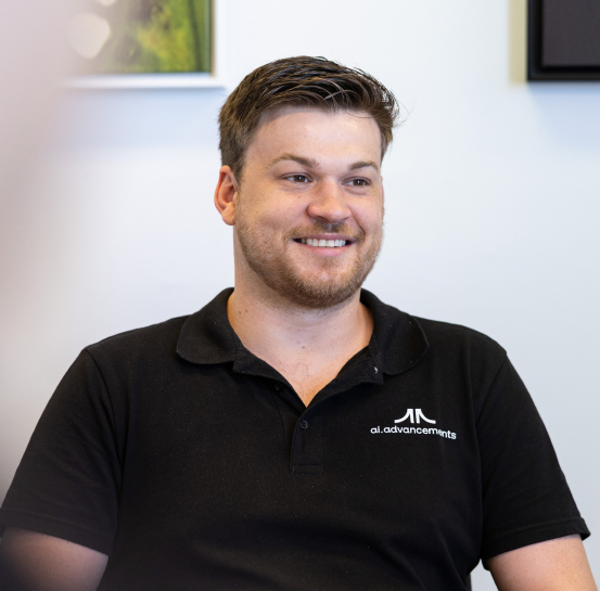Smiling AI Advancements consultant with short curly hair in a black polo shirt, representing AI Chatbots development and implementation services
