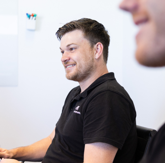 AI Advancements professional smiling while working at a computer in a bright office, representing Computer Vision services