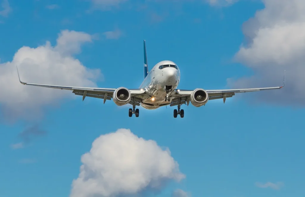 Commercial passenger aircraft in flight with landing gear down against a bright blue sky with white clouds, representing the aviation industry sector for RTO course creation